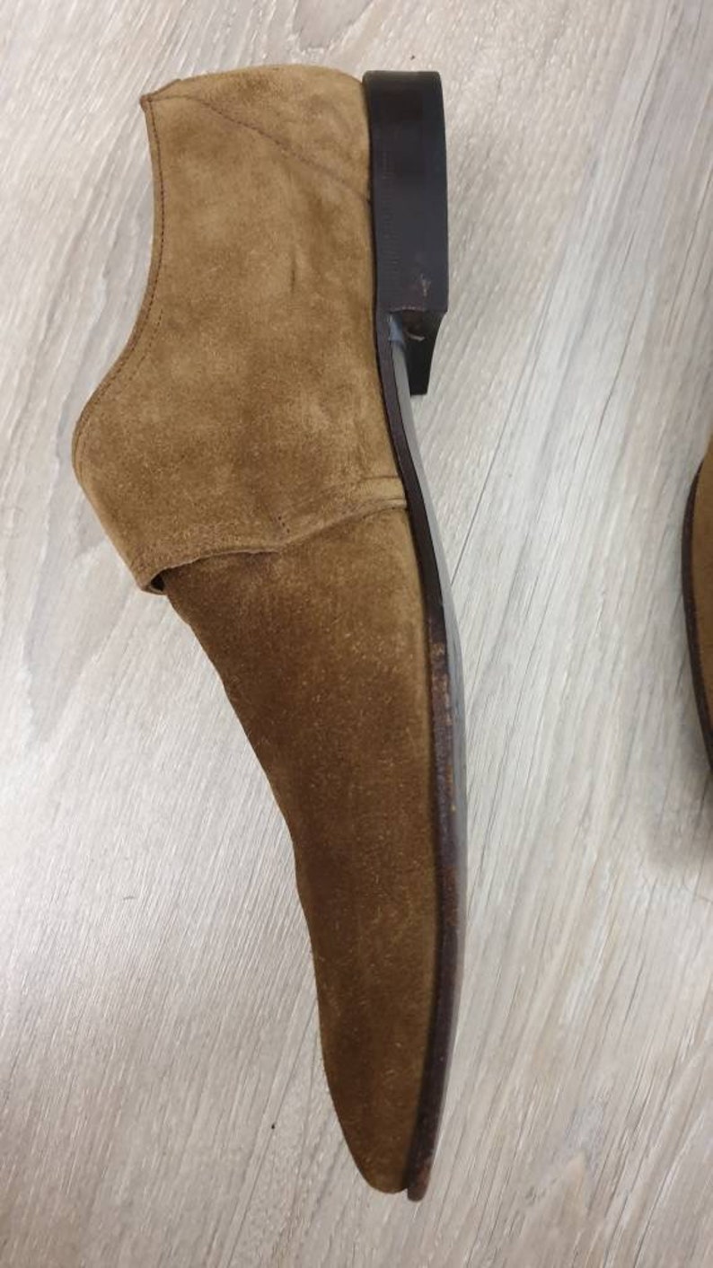 May include: A brown suede leather dress shoe with a black leather sole.