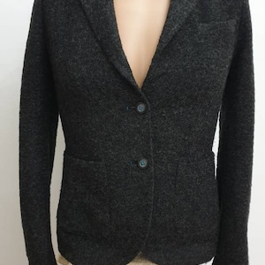 May include: A dark gray blazer with a notched collar, two pockets, and three buttons. The blazer is made of a textured fabric.