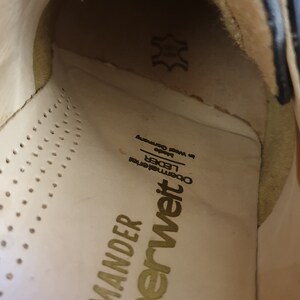 May include: Close-up of the inside of a white shoe with gold lettering that reads "Superweit" and "Salamander" with the words "OBERWEITE" and "LEDER" in smaller font. The shoe is made of leather.