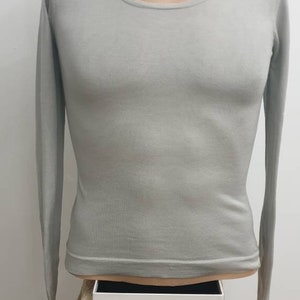 Peut inclure: Un t-shirt à manches longues gris clair avec un col rond.