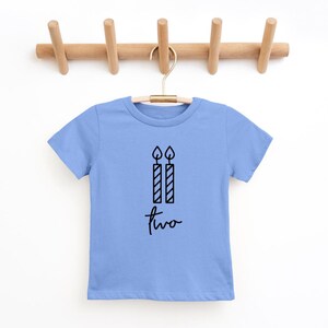 May include: A light blue t-shirt with a black graphic of two candles and the word "two" written in cursive.