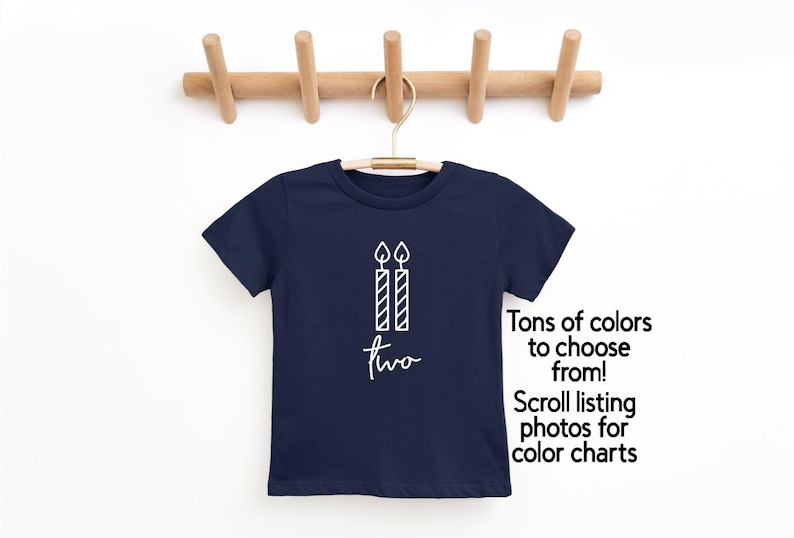 May include: Navy blue t-shirt with a white graphic of two candles and the word "two". The text "Tons of colors to choose from! Scroll listing photos for color charts" is also visible.
