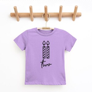 May include: A lavender short-sleeved t-shirt with a black graphic of two birthday candles and the word "two" written in cursive.