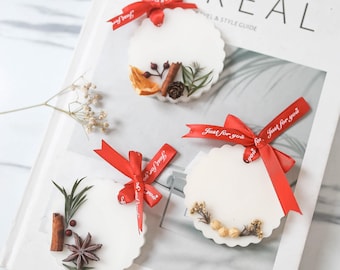 May include: Three white round wax melts with dried flowers and spices. Each melt has a red ribbon tied around it with the text "Just for you" printed on the ribbon.