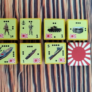Op de afbeelding: Een set van acht gele dobbelstenen met rood-witte Japanse vlagontwerpen. De dobbelstenen tonen verschillende militaire eenheden, waaronder soldaten, tanks, schepen en een bunker. De dobbelstenen zijn genummerd 1, 5 en 14.