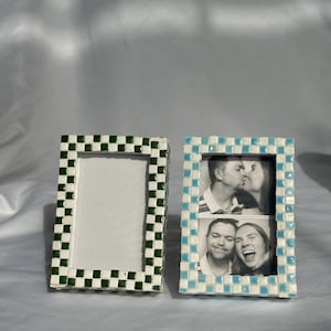 Könnte beinhalten: Zwei rechteckige Fotorahmen. Ein Rahmen hat ein grün-weißes Karomuster, der andere ein blau-weißes Karomuster. Der zweite Rahmen enthält zwei Schwarz-Weiß-Fotos von Personen.