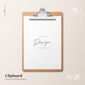 May include: A brown clipboard with a silver metal clip holding a white sheet of paper. The paper features the black printed text "YOUR Design HERE" centered on the page. This mockup is designed for displaying A4 paper designs and documents.