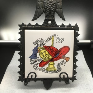 Classic FW Becker Fireman&#39;s ceramic tile trivet in heavy black iron frame with stars and Eagle motif