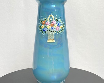 May include: A blue iridescent glass vase with a painted design of a basket of flowers. The flowers are pink, yellow, orange, and blue.