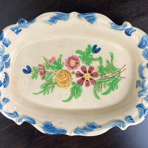 May include: A white oval serving tray with blue and white floral accents. The tray has two handles and a floral design in the center.