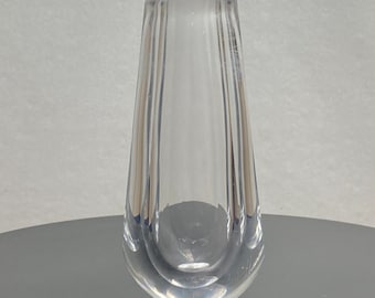 May include: A clear glass vase with a ribbed design. The vase is tall and narrow, with a rounded bottom.