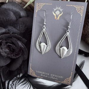May include: A pair of silver-toned teardrop earrings with a textured design. Each earring features a central, smooth, teardrop-shaped element. The earrings are displayed on a gray card with the text "Vesperine Jewellery Handmade in Australia".