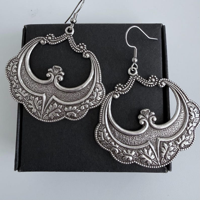 Pu&ograve; includere: Un set di tre tazze in ceramica con finitura opaca e macchiettata. Le tazze sono nei toni del crema, grigio chiaro e grigio scuro. Ogni tazza ha un design semplice e minimalista.