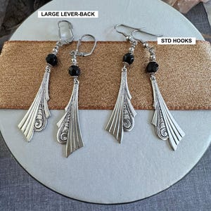 Op de afbeelding: Drie paar oorbellen met zwarte kralen en zilveren filigraanontwerpen. De oorbellen worden getoond op een bruin lint met de tekst "LARGE LEVER-BACK" en "STD HOOKS".