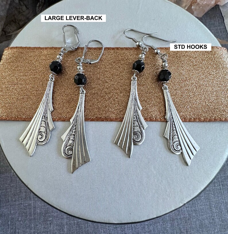Op de afbeelding: Drie paar oorbellen met zwarte kralen en zilveren filigraanontwerpen. De oorbellen worden getoond op een bruin lint met de tekst "LARGE LEVER-BACK" en "STD HOOKS".