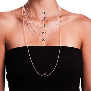 May include: A display of silver chain necklaces in various lengths, including 14, 16, 18, 20, 22, and 32 inches. The necklaces are shown against a person's torso, demonstrating how each length hangs.