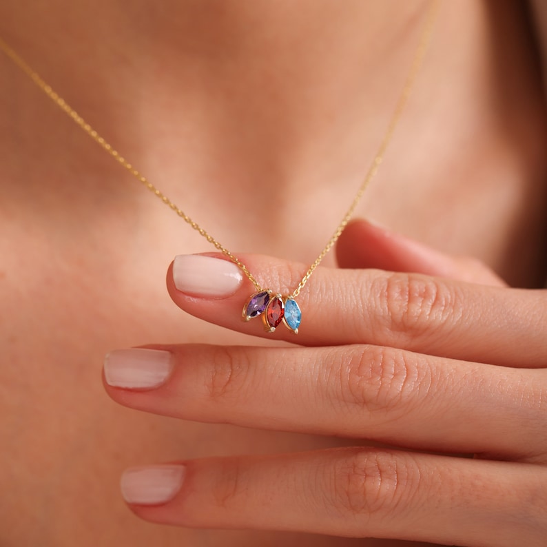 Pu&ograve; includere: Una collana con catena d'oro con un ciondolo con tre piccole pietre preziose a forma di marquise: una rossa, una viola e una blu.