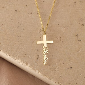 May include: Gold necklace with a cross pendant featuring the name "Christina" engraved on it.