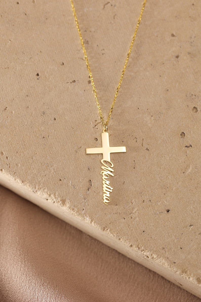 May include: Gold necklace with a cross pendant featuring the name "Christina" engraved on it.