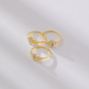 Puede incluir: Tres anillos de oro con delicados dise&ntilde;os florales. Cada anillo presenta un peque&ntilde;o engaste de forma ovalada con un motivo floral diferente.