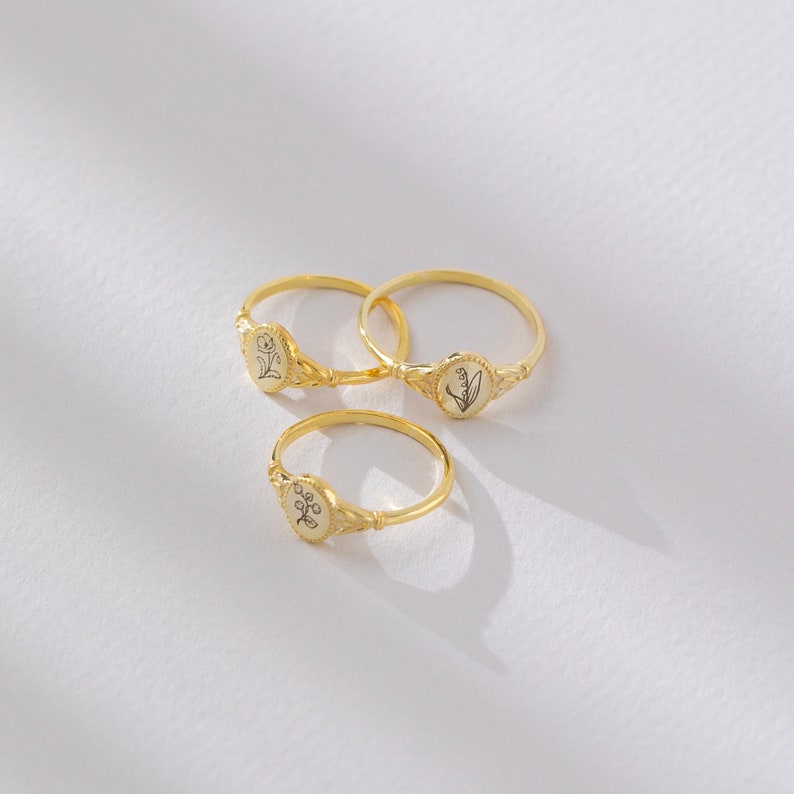 Puede incluir: Tres anillos de oro con delicados dise&ntilde;os florales. Cada anillo presenta un peque&ntilde;o engaste de forma ovalada con un motivo floral diferente.
