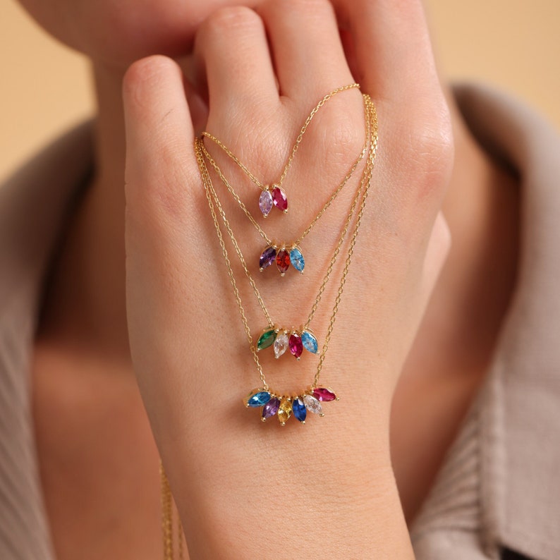Pu&ograve; includere: Una collana d'oro a pi&ugrave; strati con un design a cascata di pietre preziose a forma di marquise colorate. La collana presenta una variet&agrave; di colori, tra cui rosso, rosa, blu, verde e viola.