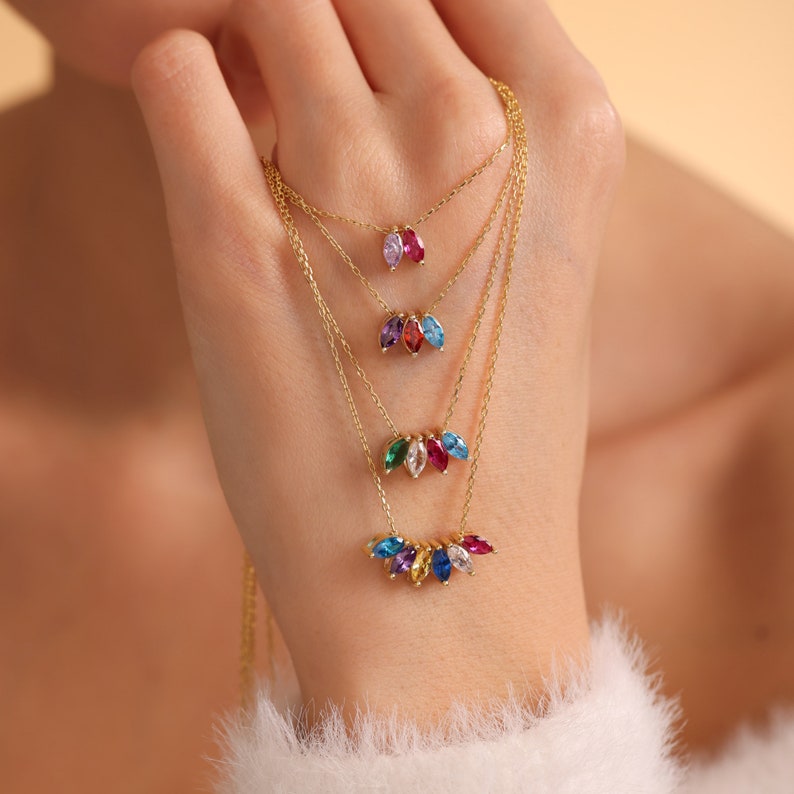 Pu&ograve; includere: Collane d'oro a strati con ciondoli colorati a forma di marquise. Le collane presentano una variet&agrave; di colori, tra cui rosso, blu, verde, viola e giallo.