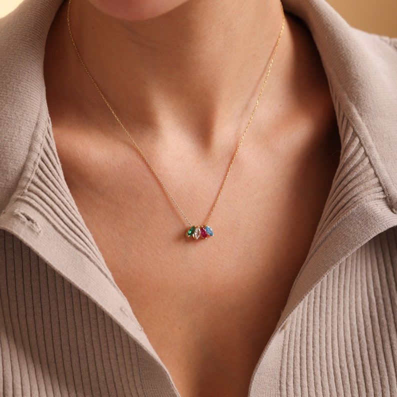 Pu&ograve; includere: Una collana con catena d'oro con un piccolo ciondolo con tre pietre preziose colorate: verde, blu e rosso.