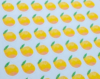 Peut inclure: Une feuille d'autocollants avec 49 petits autocollants de fruits ronds, jaunes et orange. Les autocollants ont un contour blanc et une tige verte. Les autocollants sont disposés en grille sur une feuille de papier blanche.