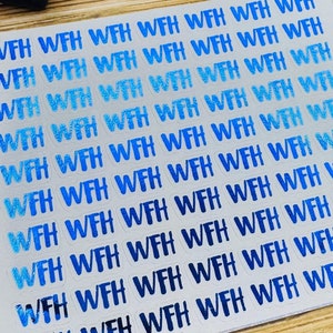 May include: A white sticker sheet with the text "WFH" repeated in a blue gradient pattern. The sticker sheet is on a wooden surface with other small objects.