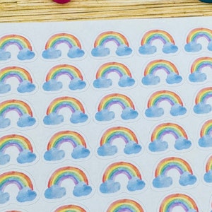 May include: A sheet of rainbow stickers with 36 individual stickers. Each sticker features a watercolor rainbow with clouds.