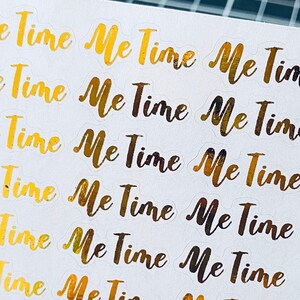 Peut inclure: Une feuille d'autocollants en feuille d'or avec la phrase "Me Time" répétée plusieurs fois.