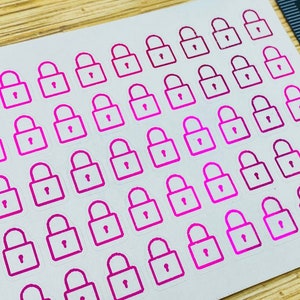 May include: A sheet of pink and white lock stickers. The stickers are arranged in rows and columns on a white background. There are 30 stickers in total.