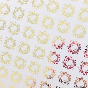 May include: A sheet of gold and red foil stickers with a sunburst design. The stickers are arranged in rows and columns on a white background.