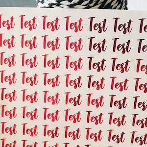 Könnte beinhalten: Ein Blatt weißes Papier mit den Worten "Test Test Test Test Test Test Test" 12 Mal in roter Kursivschrift wiederholt.