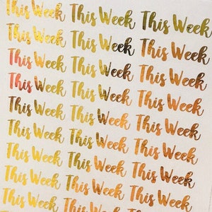 May include: A sheet of gold foil stickers with the words "This Week" repeated multiple times. The stickers are on a white background.
