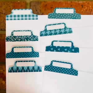 May include: Set of eight blue and white patterned tab dividers with a blank white space for writing. The dividers have a variety of patterns including gingham, geometric, and polka dots.