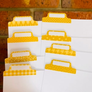 May include: Set of eight yellow patterned index cards with white borders and blank spaces for writing. The patterns include polka dots, geometric shapes, and zigzags.