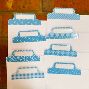 May include: Eight blue patterned index tabs with white labels. The patterns include geometric shapes, polka dots, and gingham.