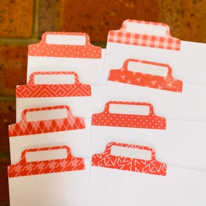 May include: Eight red and white patterned index tabs with white labels. The tabs have different patterns including gingham, polka dots, and geometric shapes.