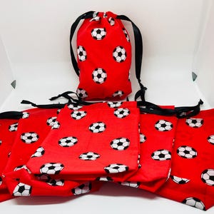 Op de afbeelding: Set van acht rode trekzakjes met zwarte trekkoorden. De zakjes zijn versierd met een wit voetbalpatroon.