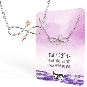 May include: A silver infinity necklace with a rose gold arrow charm. The necklace comes with a card that reads "Malin Arrow - You have to face setbacks in order to move forward. Happy Kisses".