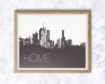 May include: A framed black and white print of a city skyline with the word "HOME" printed below. The print is in a light wood frame.