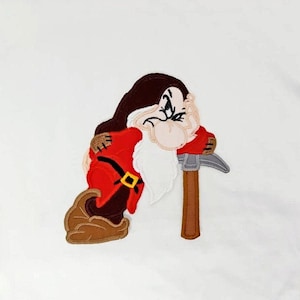 May include: An embroidered patch of a grumpy dwarf from the Disney film Snow White and the Seven Dwarfs. The dwarf is wearing a red shirt and a brown hat. He is holding a pickaxe in his right hand and is looking to the left.