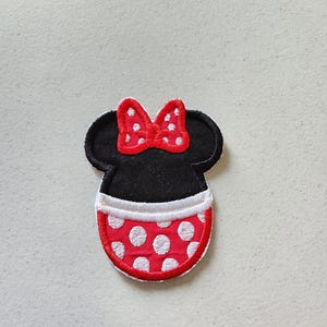 May include: Red and white polka dot fabric iron-on patch featuring a black and white cartoon mouse head with a red bow.