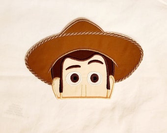 Peut inclure: Patch brodé de Woody de Toy Story. Le patch représente le visage de Woody avec son chapeau marron signature et une bordure en corde marron clair.