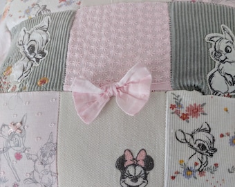May include: A patchwork pillow featuring various fabric squares in shades of pink, grey, and white. The design includes embroidered images of Minnie Mouse, Bambi, and Thumper, floral patterns, textured corduroy, and a central light pink fabric bow.