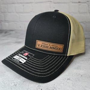 May include: Black and tan trucker hat with a brown leather patch that says "Dillon & Jenny V.XXXIII.MMXXI".