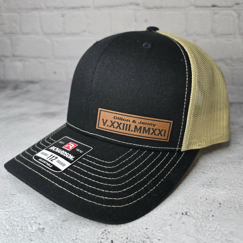 May include: Black and tan trucker hat with a brown leather patch that says "Dillon & Jenny V.XXXIII.MMXXI".