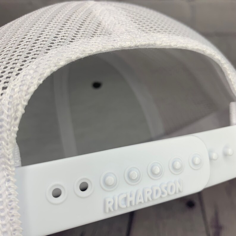 May include: White mesh trucker hat with a white adjustable strap and the word "RICHARDSON" embossed on the strap.